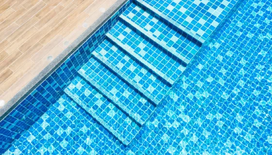 Water ripples on blue tiled swimming pool background. View of nice blue swimming pool water surface, top view